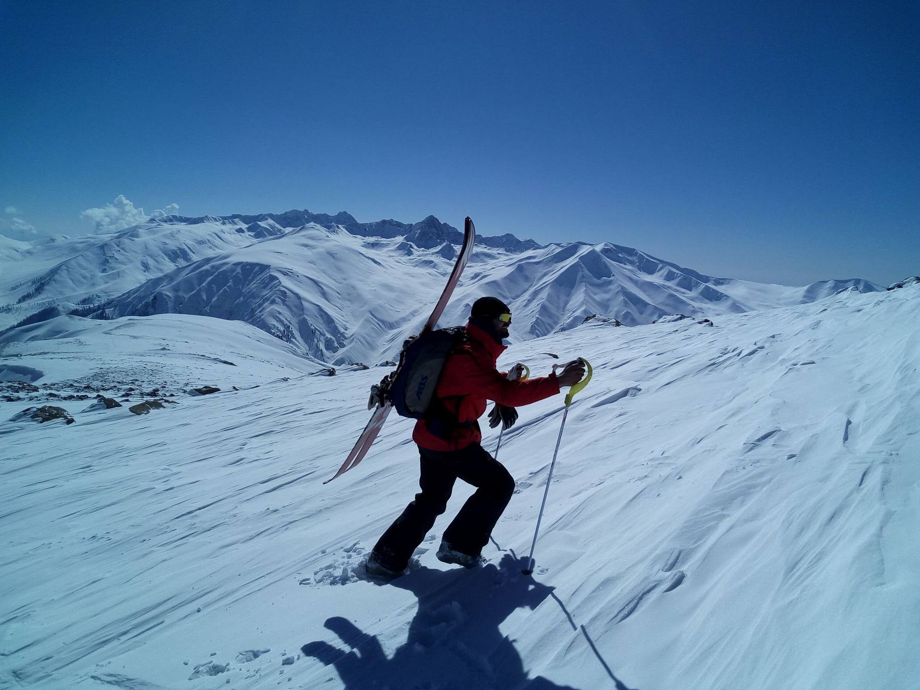 Snowboarder climbing a ridge toward a Gulmarg summit